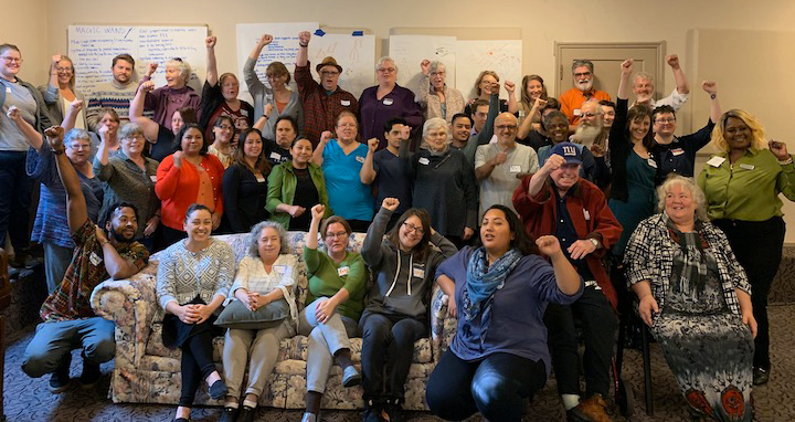 A large group of ROC members holding up their fists at an advocacy training day in Salem